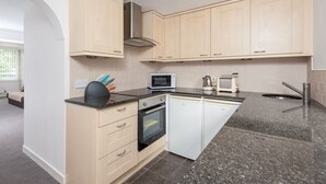 Eine moderne Küche mit hellen Holzschränken, einem Backofen, einer Mikrowelle und einem Geschirrspüler.