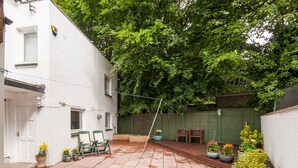 Ein Innenhof mit einem weißen Gebäude, einem grünen Zaun und Kübelpflanzen.