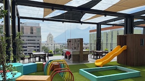 A rooftop terrace with a play area, seating, and a view of the cityscape.