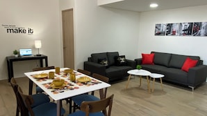A modern living room with a dining table set for four, a sofa, and a small coffee table.