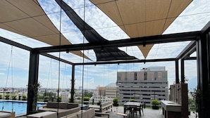 A rooftop patio with outdoor seating, a swing, and a pool.
