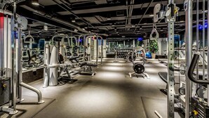A gym with various exercise machines, mirrors, and weights. - Canal Walk District Apartments by Landing (Indianapolis)
