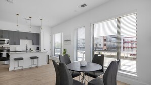 A modern kitchen with grey cabinets, a stainless steel oven, and a white countertop. There is a dining area with a round table and four chairs. - Landing Apartments Denton (Denton)