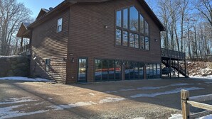 A wooden cabin with large windows and a stone foundation. - Large, Family-Friendly Lake Home, On Snowmobile/ATV Trails, W/D, Firepit (Harshaw)