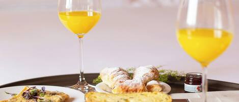A breakfast tray with various dishes and glasses of orange juice on a table in a hotel room.