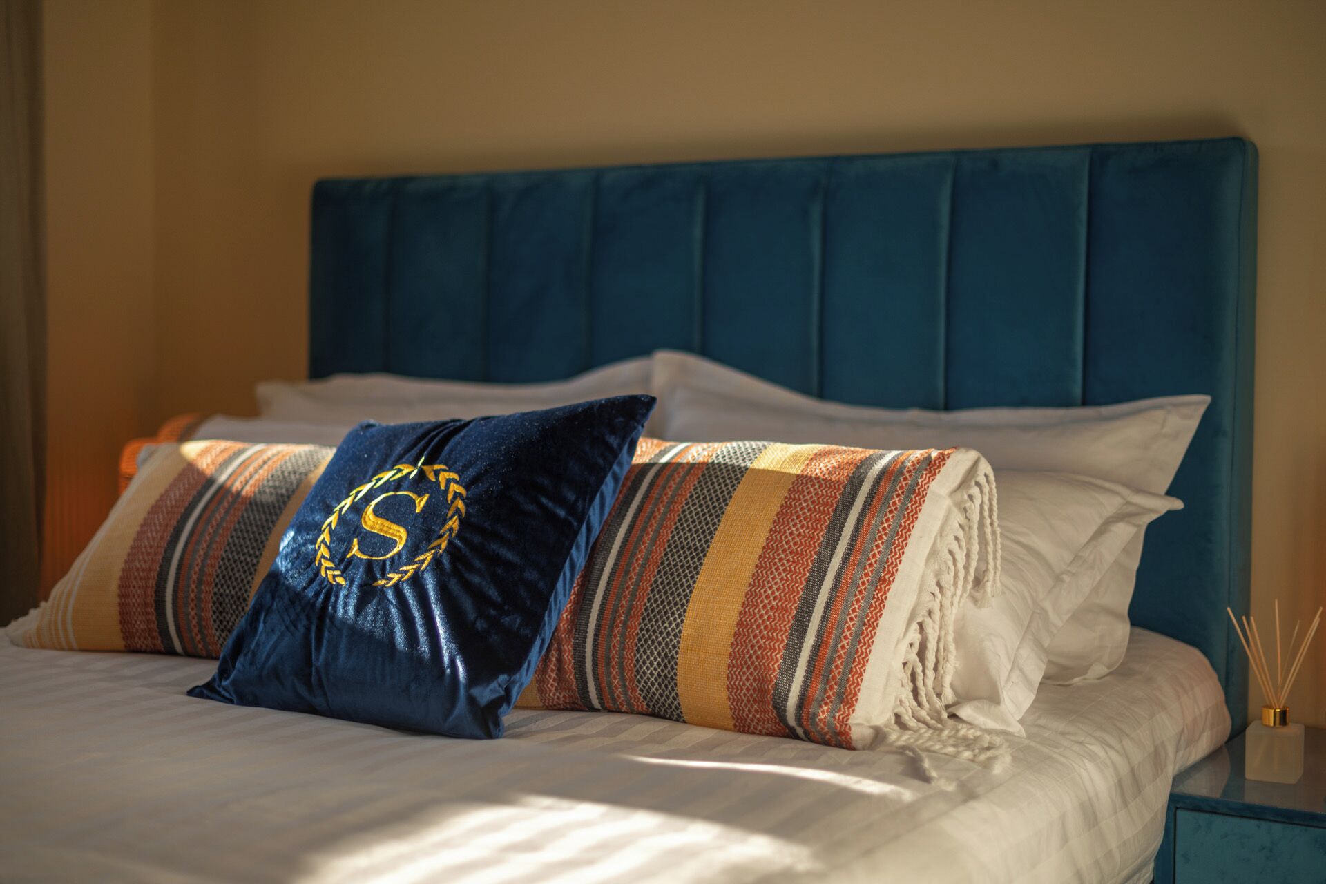 A bed with a blue headboard, white bedding, and decorative pillows.