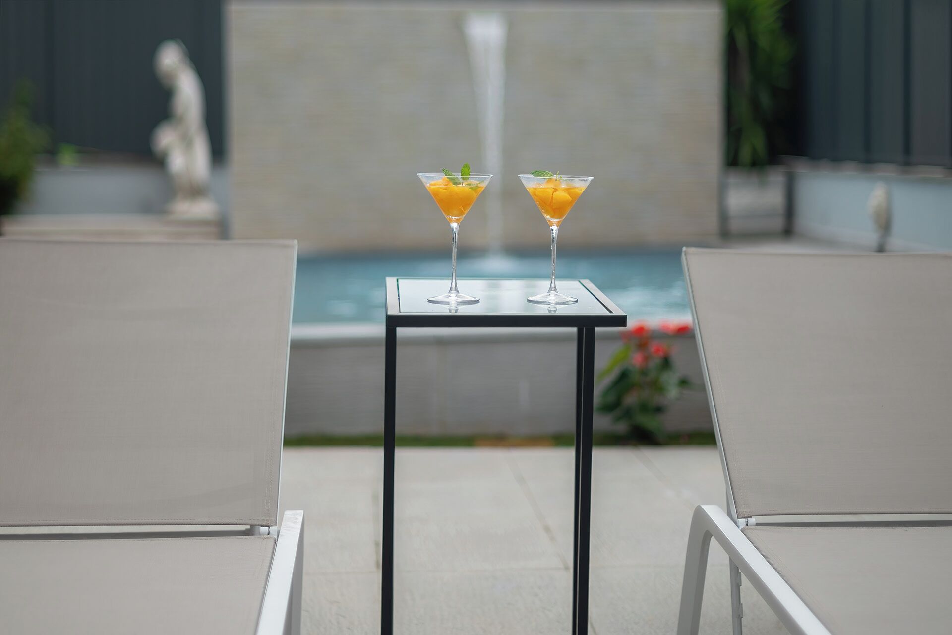 Zwei Martini-Gläser mit einem gelb-orangefarbenen Getränk auf einem kleinen Tisch im Freien.