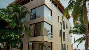 A modern building with large windows and a balcony, surrounded by palm trees. - Hotel UNNU (Santa María Huatulco)