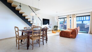 Un salon moderne comprenant un coin repas, un escalier et de grandes fenêtres.