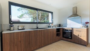 Une cuisine moderne avec des meubles en bois, une grande fenêtre et un four encastré.