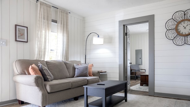 A living room with a sofa, a coffee table, a lamp, and a wall clock.