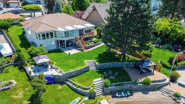 Una casa grande con un patio trasero amplio, que incluye una piscina, un puente de piedra y un muelle para embarcaciones.