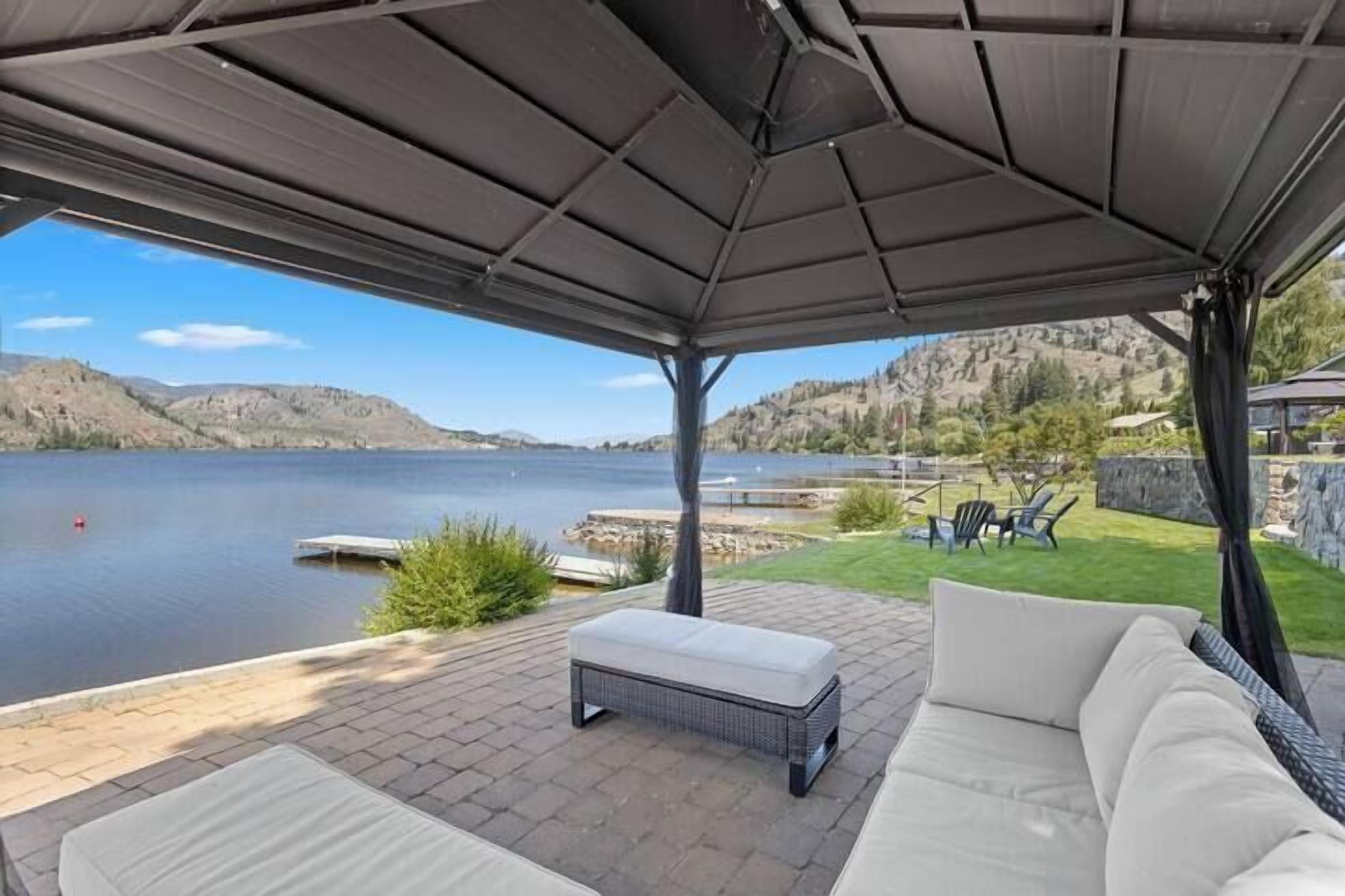 A covered outdoor seating area with a view of a lake and mountains.