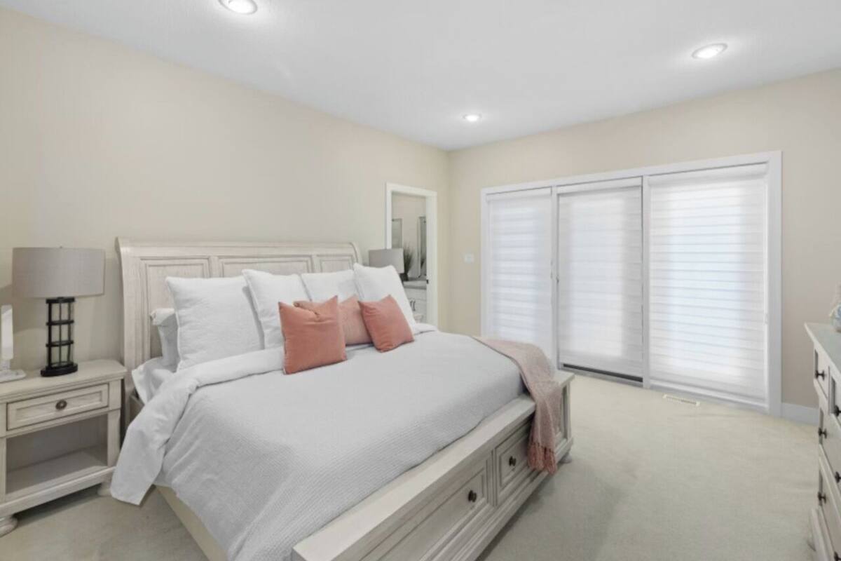 Un dormitorio con cama, mesitas de noche, cómoda y vestidor.