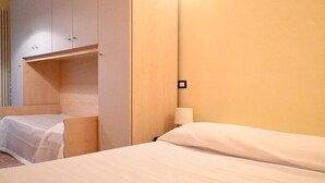 Une chambre d’hôtel avec un lit, une table de chevet, une lampe et une armoire.
