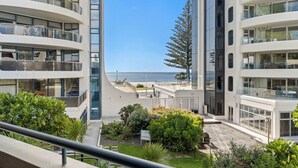 Un edificio moderno de varios pisos con balcones, vistas al mar y jardines ajardinados.