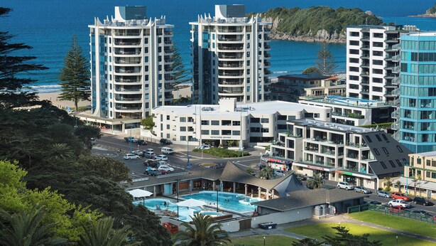 Un hotel costero con varios edificios altos, una piscina y vistas al océano.