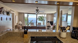 A kitchen with granite countertops, a built-in stove, and a view of the ocean.