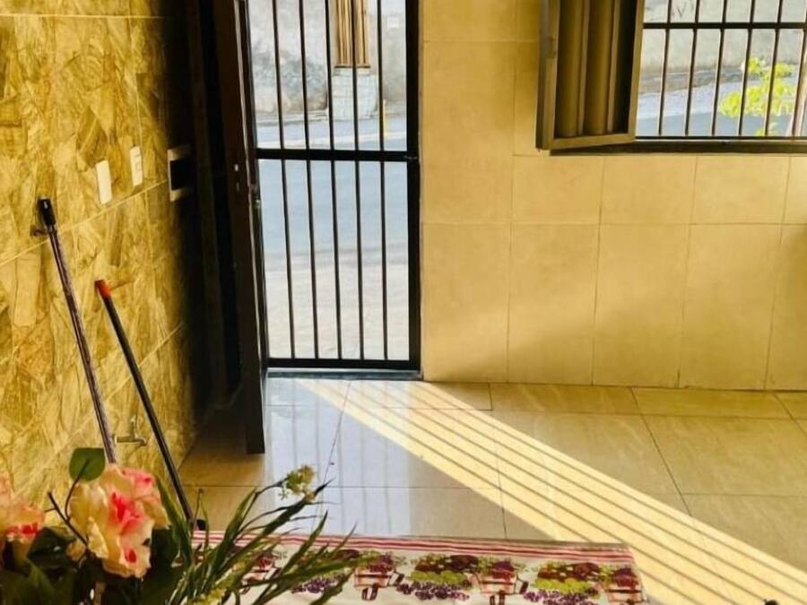 A room with a marble wall, a black gate, a sink, and a floral-patterned rug.