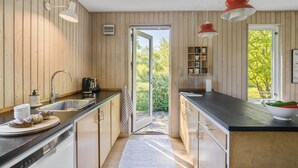 A modern kitchen with wooden walls, a large window, and a view of greenery. - Cozy home in Vejby with WiFi (Vejby)