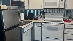 Una cocina moderna con electrodomésticos de acero inoxidable, armarios blancos y un salpicadero a rayas.