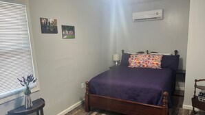 Un dormitorio con una cama de madera, una mesita con un florero y dos cuadros colgados en la pared.