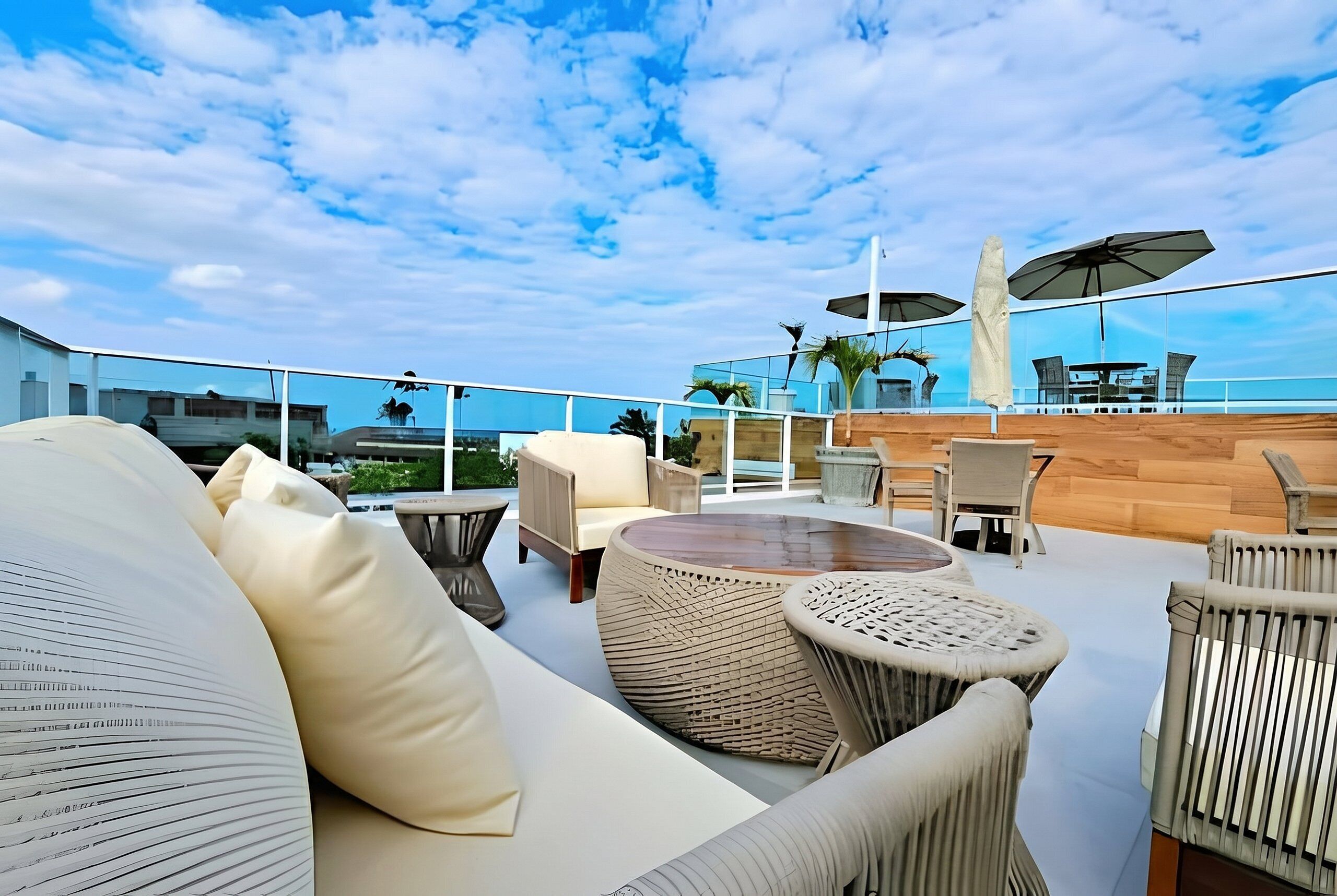Un salon sur le toit, doté d’un espace extérieur aménagé, d’une terrasse en bois et d’une vue sur l’océan.