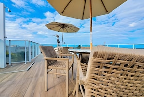 A deck with wicker furniture, a table, and an umbrella.
