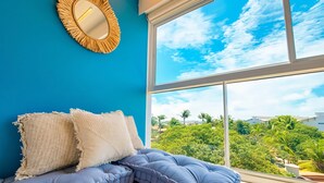 A room with a bed, a mirror, and a large window with a view of greenery. - Porto de Galinhas Center | 3 Min from the Beach (Ipojuca)