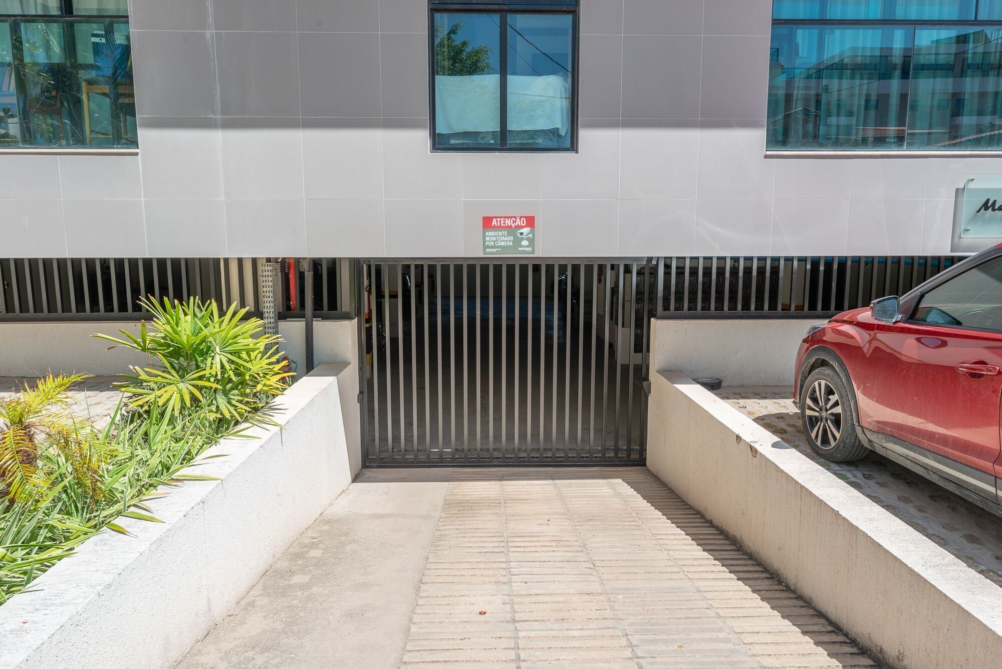 A gated entrance to a building with a red car parked on the right.