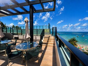 A rooftop terrace with outdoor seating, a glass balustrade, and a view of the ocean. - Amazing flat on the sand (Ipojuca)