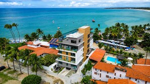 A coastal hotel with modern architecture, a pool, and a view of the ocean.