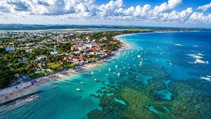 An aerial view of a coastal town with a beach, boats, and clear blue waters. - Beachfront with ocean view (Ipojuca)