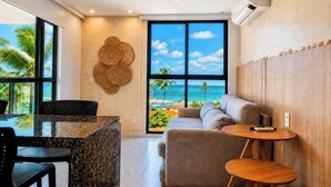 A modern room with a large window, a sofa, a small table, and a decorative wall piece. - Beachfront with ocean view (Ipojuca)