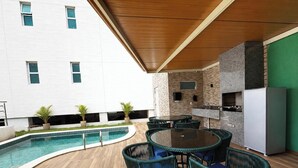 An outdoor patio with a pool, seating area, and a kitchenette. - Luxury Apartment Near Porto's Natural Pools (Ipojuca)