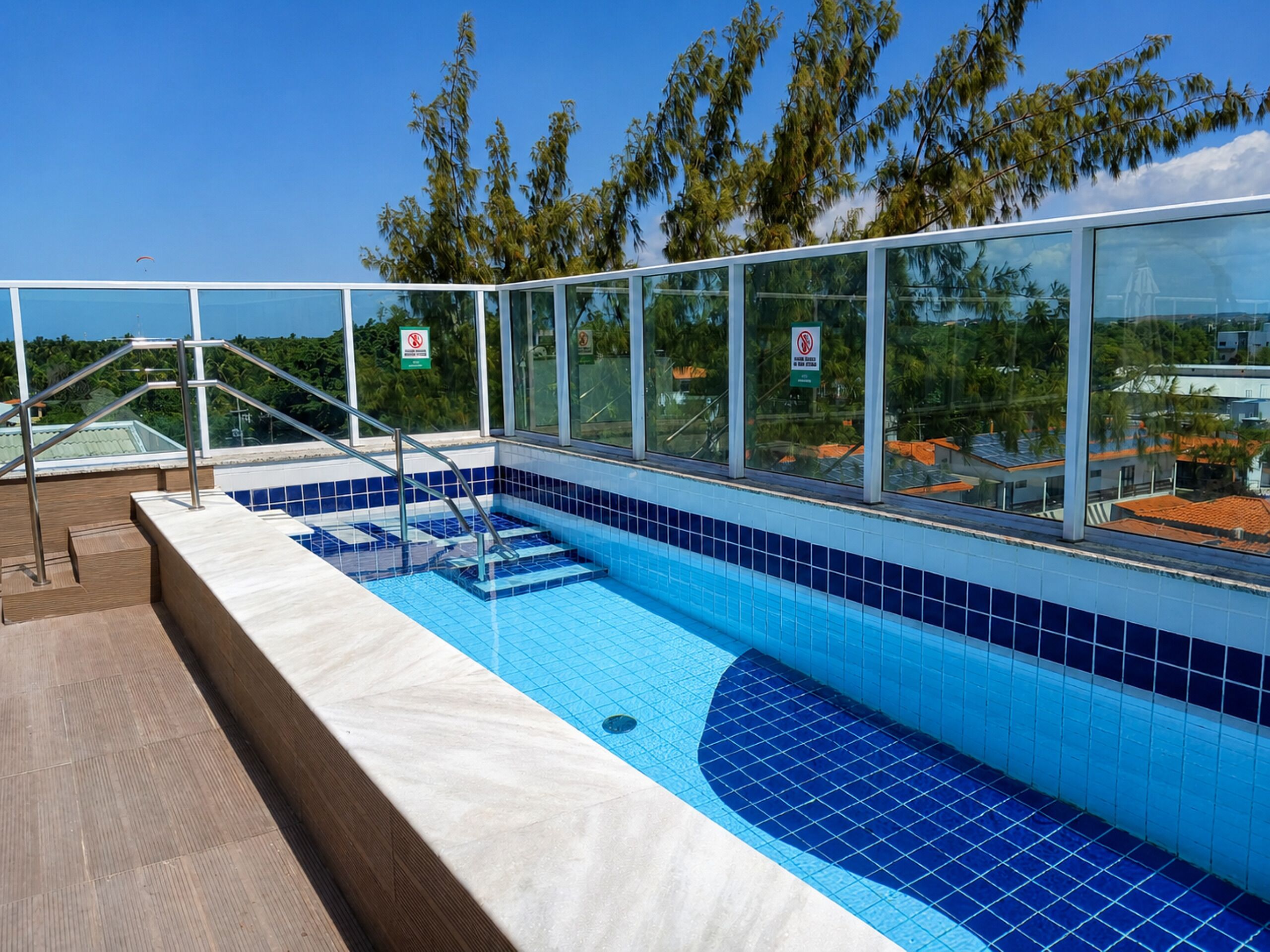 A swimming pool with glass railings, a no diving sign, and a view of the surrounding area.