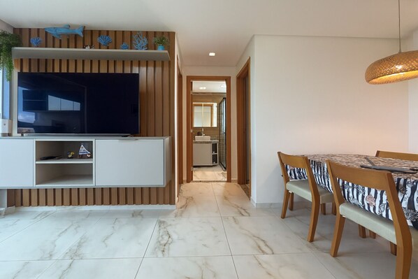 A modern living room with a TV, entertainment unit, and dining area.