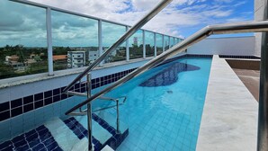 En pool på taket med utsikt över stadsbilden, metallräcken och kakelgolv.
