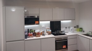 A modern kitchen with white cabinets, a built-in oven, a microwave, and a sink. - Room-charming Loughton Apartment With Ba (Loughton)