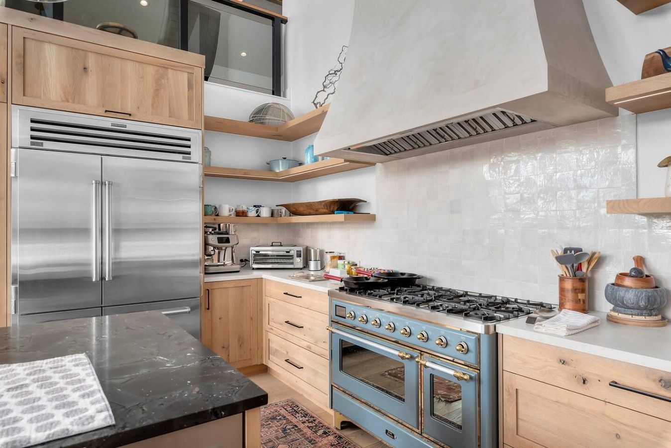 A modern kitchen with stainless steel appliances, wooden cabinets, and a blue stove.
