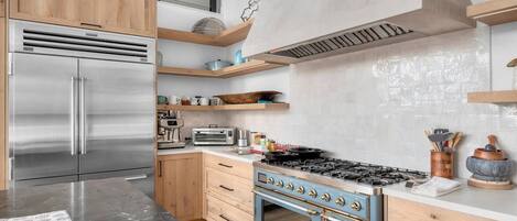 A modern kitchen with stainless steel appliances, wooden cabinets, and a blue stove.