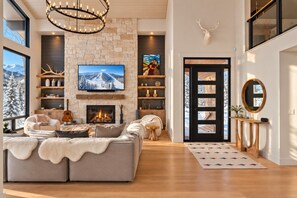 A modern living room with a fireplace, large windows, and a cozy seating area.