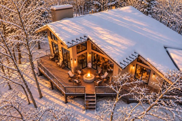 A modern house with a deck, outdoor seating, and a fire pit.