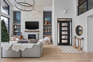 A modern living room with a sectional sofa, a fireplace, a mounted TV, and a deer head decoration. - Scenic Alpine Getaway, Hot Tub, Sauna, Views (Park City)