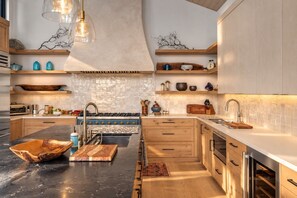 A modern kitchen with a central island, wooden cabinets, and a variety of kitchen appliances.