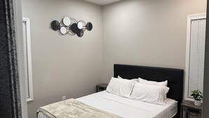 Ein modernes Schlafzimmer mit Bett, Nachttischen, einer Bank und einer Wandleuchte.