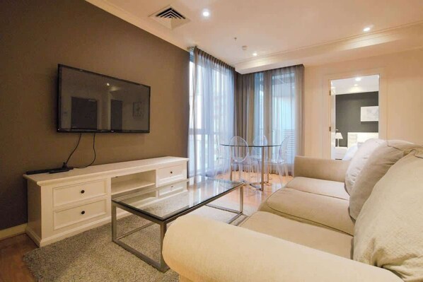 Relax in this stylish living room with a flat-screen TV, glass-top coffee table, and comfortable sofa.