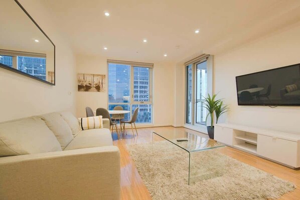 Enjoy the city view from the large window in this stylish living room, featuring a flat-screen TV and comfortable sofa.