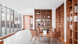 A modern interior with a dining area, large wooden bookshelves, and a view through large windows.