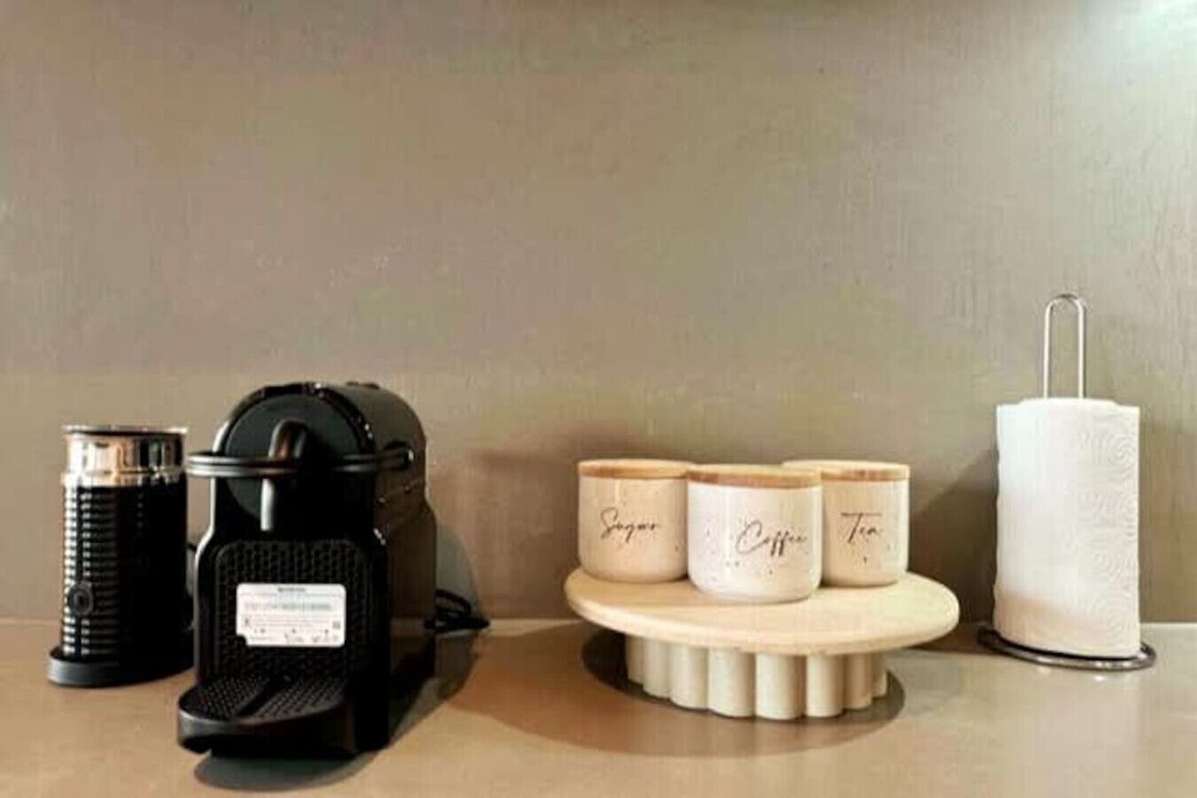 A coffee maker, two containers labeled 'Sugar' and 'Coffee', and a paper towel holder on a countertop.